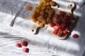 Two handfuls of fresh red and yellow raspberry on white wooden kitchen boards with copy space Royalty Free Stock Photo
