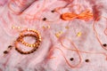 Two handmade shamballa bracelets on a pink tissue with scattered beads and orange cotton threads