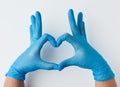 Two hands in blue latex sterile medical gloves shows a gesture of the heart on a white background, concept of goodness Royalty Free Stock Photo