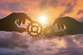 Two hands businessman holding gears on the background of the sky in the sun, connecting the puzzle pieces. creation. Royalty Free Stock Photo