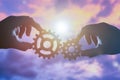 Two hands businessman holding gears on the background of the sky in the sun, connecting the puzzle pieces. creation. mechanism. Royalty Free Stock Photo