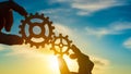 Two hands of businessmen connect gears to a puzzle on a sunset background. Business concept idea, partnership Royalty Free Stock Photo