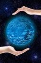 Two hands carefully hold a blue planet against the