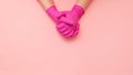 Two hands clasped together in hygienic pink gloves