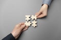 Two hands connect puzzles on a grey background. Cooperation and teamwork in business. Collaboration people for success
