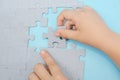 Two hands connecting puzzles on blue.wooden puzzle Teamwork, partnership, business idea, cooperation management concept