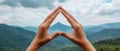 Hands Forming Triangle Shape Against Scenic Mountain Landscape Under Blue Sky With Clouds Royalty Free Stock Photo