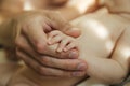 Two hands: dad holds a newborn baby by the arm, his face is not visible