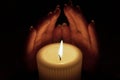 Two hands are raised over a burning candle Royalty Free Stock Photo