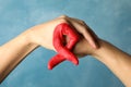 Two hands depict AIDS awareness sign against blue background