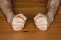 Two hands fists on wooden table clench hairy man fists symbol anger closeup