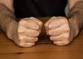 Two hands fists on wooden table clench hairy man fists symbol anger closeup