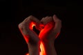 Two hands folded in the shape of a heart, light inside. Clench your hands, symbol of love. Royalty Free Stock Photo