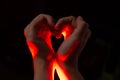 Two hands folded in the shape of a heart, light inside. Clench your hands, symbol of love. Royalty Free Stock Photo