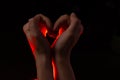 Two hands folded in the shape of a heart, light inside. Clench your hands, symbol of love. Royalty Free Stock Photo