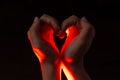 Two hands folded in the shape of a heart, light inside. Clench your hands, symbol of love. Royalty Free Stock Photo