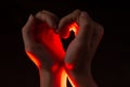 Two hands folded in the shape of a heart, light inside. Clench your hands, symbol of love. Royalty Free Stock Photo