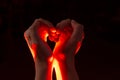 Two hands folded in the shape of a heart, light inside. Clench your hands, symbol of love. Royalty Free Stock Photo