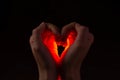 Two hands folded in the shape of a heart, light inside. Clench your hands, symbol of love. Royalty Free Stock Photo