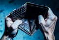 Two hands gripping an empty brown leather wallet tightly under a strong overhead light casting shadows, visible Royalty Free Stock Photo