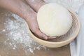 Two hands holding bread dough, proofing basket Royalty Free Stock Photo