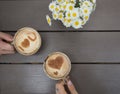 Two hands hold cups of coffee with cinnamon hearts on milk foam. love concept Royalty Free Stock Photo