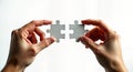 Two hands hold puzzle pieces. Hands connect puzzle elements. Image shows problem-solving, success concept. Solution, strategy.