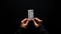 Two hands hold a small, rectangular ticket against a dark background