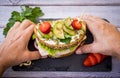 Two hands hold a three-layer wholemeal sandwich with roasted turkey with lettuce and tomato, salami with onion and avocado with Royalty Free Stock Photo