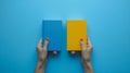 Two Hands Holding Blue and Yellow Book Royalty Free Stock Photo