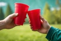 Two hands holding cups, toasting against a blurred nature background Royalty Free Stock Photo
