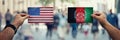 Two hands holding different flags, US vs Afghanistan on politics arena over crowded street background. Diplomacy future strategy,