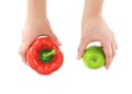 Two hands holding a fresh raw vegetable red bell pepper and a ripe green apple isolated on white background. View from Royalty Free Stock Photo