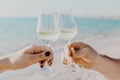 Two hands holding glasses with white wine on sea background in Italy Royalty Free Stock Photo