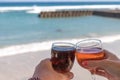 Two hands holding glasses with wine on sea background. Female and male hands with wine glasses. Royalty Free Stock Photo