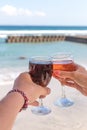 Two hands holding glasses with wine on sea background. Female and male hands with wine glasses. Royalty Free Stock Photo
