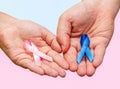 Two hands holding two Pink and Blue ribbons for the Pink October and Blue November campaigns to support life and raise awareness