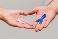 Two hands holding two Pink and Blue ribbons for the Pink October and Blue November campaigns to support life and raise awareness