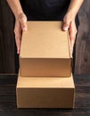 Woman holding empty cardboard boxes on a dark wooden background. Creating a model Royalty Free Stock Photo