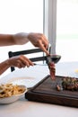 two hands holding steak bite on cutting board bringing it to their plate