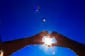 Two hands holding the sun on a blue sky background Royalty Free Stock Photo