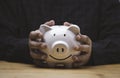 Two hands holding white smile piggy saving bank on wooden table for money save deposit and financial banking concept Royalty Free Stock Photo