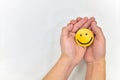 Two hands hugging a yellow smiling face on a white background. Happy together and share happiness concepts