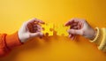 Two hands join yellow puzzle pieces on orange background. People cooperate, connect parts showing teamwork and problem solving Royalty Free Stock Photo