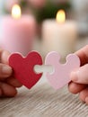 Two hands joining heart-shaped puzzle pieces with candles. Royalty Free Stock Photo