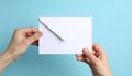 Two hands, likely female, hold a white envelope against a light blue background Royalty Free Stock Photo