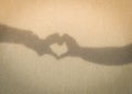 Two hands making love heart shadow symbol on the sand at the beach. Royalty Free Stock Photo