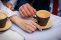 Two hands, male and female, with the wedding rings touch of brown coffee cup Royalty Free Stock Photo