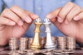 Two hands next to the dollar coin help the two chess kings duel Royalty Free Stock Photo