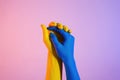 Two hands painted in yellow and blue held together against a gradient background Royalty Free Stock Photo